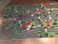 Top view of one section of the playmat showing a bus stop, gas station, a church, parking areas and streets.