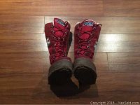 Front view of the pair of red tall Pajar boots showing laces and logo patches.