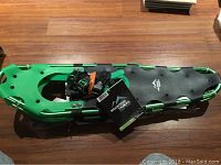 Pair of green-and-black Mountain Tracks Pro Series snowshoes showing bindings and crampons, with tags attached.
