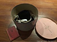 Black Eaton's hat inside original Eaton's Canada round hat box with lid shown beside it, and 1930 Kipling Just So Stories book lying on floor.