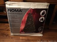 Box of NOMA Indoor Lighted Pine Tree showing brand, tree height (6.5 feet) and included 400 multi-colored pre-strung mini lights.
