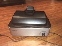 Full view of NESCO 12QT roaster air convection oven with black lid on top and power cord.