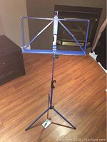 Full view of blue metal guitar music stand with adjustable height and tripod base