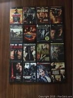 Photo showing 16 action thriller DVD cases arranged on a wooden floor.