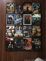 Top-down view of all 16 DVD covers arranged in a 4x4 grid on a wooden floor showing the titles and cover art.