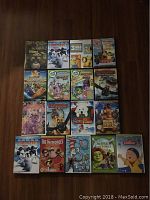 Photo showing 17 kids DVDs laid out on the floor, titles include Born to Be Wild, Happy Feet, Minions 3 Mini Movie Collection, Save the Wonder Pets!, Turbo, LeapFrog series, How to Train Your Dragon parts, My Little Pony, Santa Paws, Brother Bear, The Incredibles, Cat in the Hat, Shrek the Third, and Caillou.