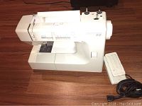 Profile view of white Kenmore Model 22 sewing machine with foot pedal and power cord.