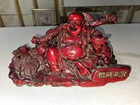 Front view of red resin Laughing Buddha with coins and toad