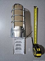 Overall view of caged jelly-jar light with tape measure and manual