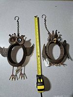 Both owl sculptures side-by-side with tape measure for scale