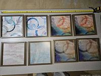 All eight framed prints laid out with tape measure for scale
