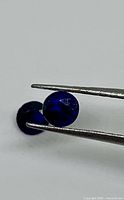 Both sapphires shown, one held in tweezers