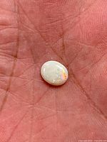White opal cabochon showing orange flash