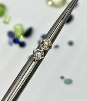 Close-up of both diamond studs held in tweezers