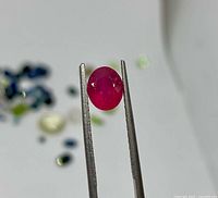 Front view of the ruby held in tweezers
