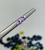 Close-up of both tourmaline studs held by tweezers