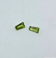 Two tapered baguette peridots on white background