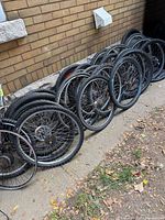 Row of multiple bicycle wheels leaned against wall