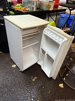 Kenmore compact fridge open showing shelves, door bins, exterior wear