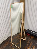 Full view of free-standing wood framed cheval mirror on wood floor