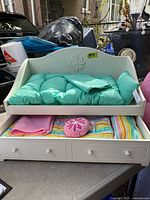 Daybed with teal bedding and drawer open showing additional bedding