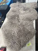 Full view of grey faux lamb rug on table