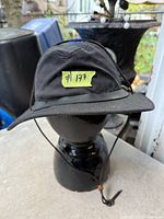 Front view of black Filson hat on stand showing brim and chin cord