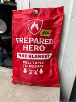 Red Prepared Hero fire blanket sealed pouch leaning against wall
