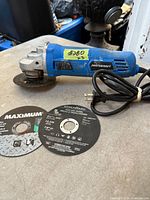 Angle grinder with attached worn cut-off wheel and power cord visible