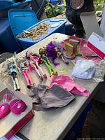 Overview of four Monster High dolls, American Girl boots, clothes and packaged items on table