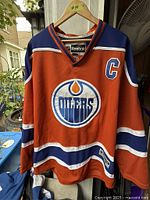 Full front view of orange Oilers jersey on hanger