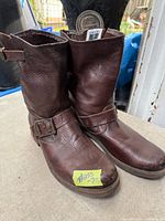 Full view of both brown leather Frye boots showing buckle and overall wear