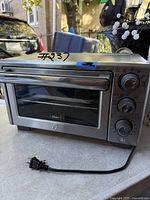 Front view of stainless steel Oster toaster oven with power cord displayed