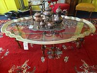 Full view of oval scalloped glass coffee table on red rug