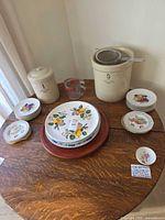 Overall view of crocks, plates, lazy Susan, strainer and measuring cup on table