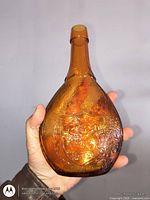 Front view showing amber pressed glass bottle with embossed fish