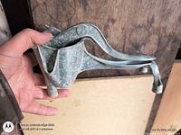 Side view of cast metal hand citrus juicer showing hinged lever and feet