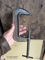 Full view of cast iron C-clamp in hand showing size and markings