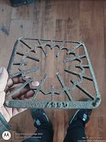 Full view of square cast iron grate held in hand