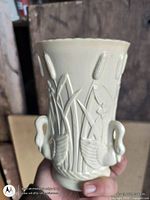Front view of cream glazed vase showing swan and cattail relief