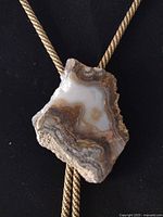 Close view of agate slab bolo on gold cord