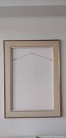 Full view of empty rectangular gold frame with cream linen liner and hanging wire