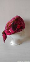 Side profile of pillbox hat on mannequin head showing leaf pattern and bow