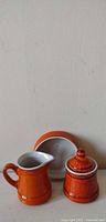Full view of three matching orange ceramic pieces