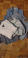 Pile of five clothing items showing denim vest, denim shirt, white blouse, striped skirt, denim bottoms