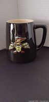 Front view of black ceramic mug showing Thunderbird relief