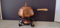 Full view of copper fondue pot on iron stand