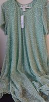 Full view of mint green polka-dot dress draped to show style and fabric