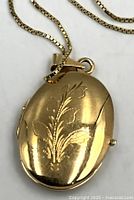 Front view of engraved 14K oval locket on chain