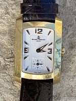 Front view of watch showing gold case, dial, numerals, seconds sub-dial